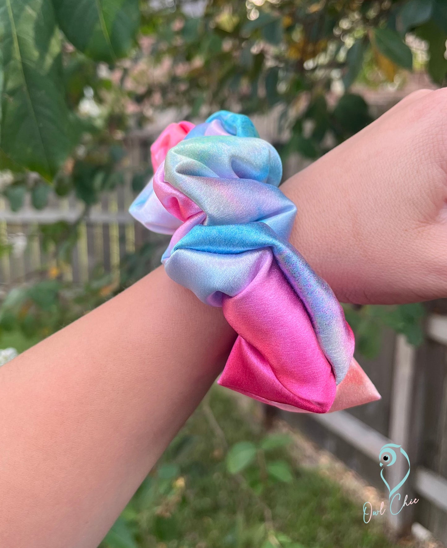 Polyester charmeuse satin scrunchie in pink, blue, and green watercolors.