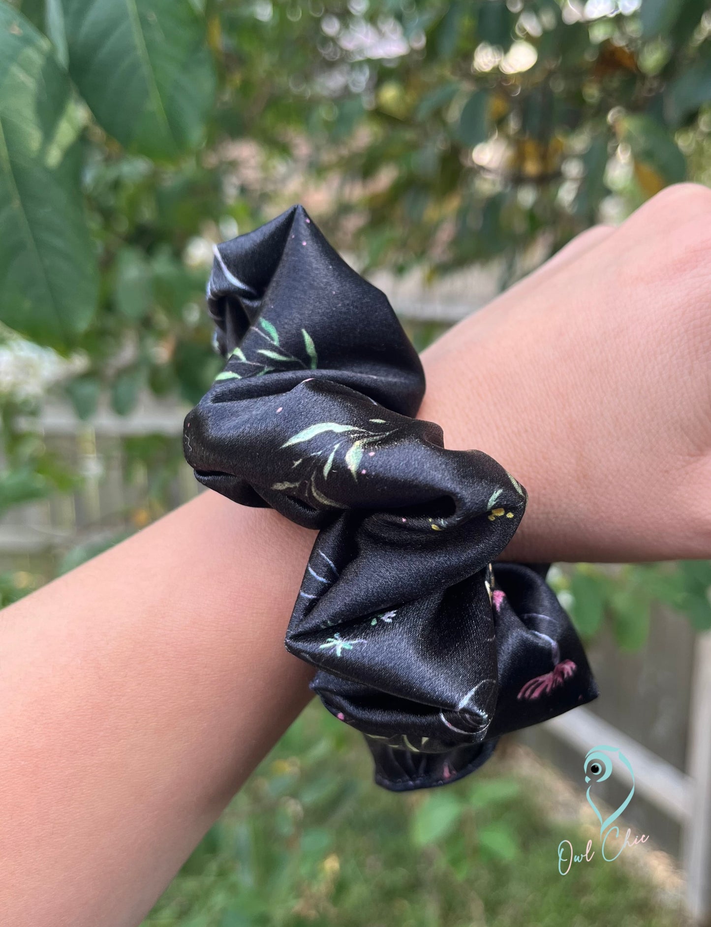Polyester charmeuse satin scrunchie in black with meadow flowers.