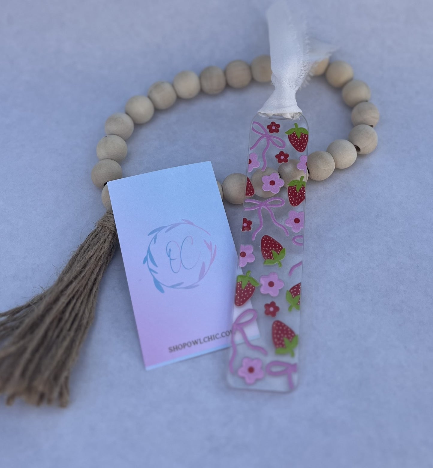 Close-up of acrylic bookmark with pink strawberries and floral pattern